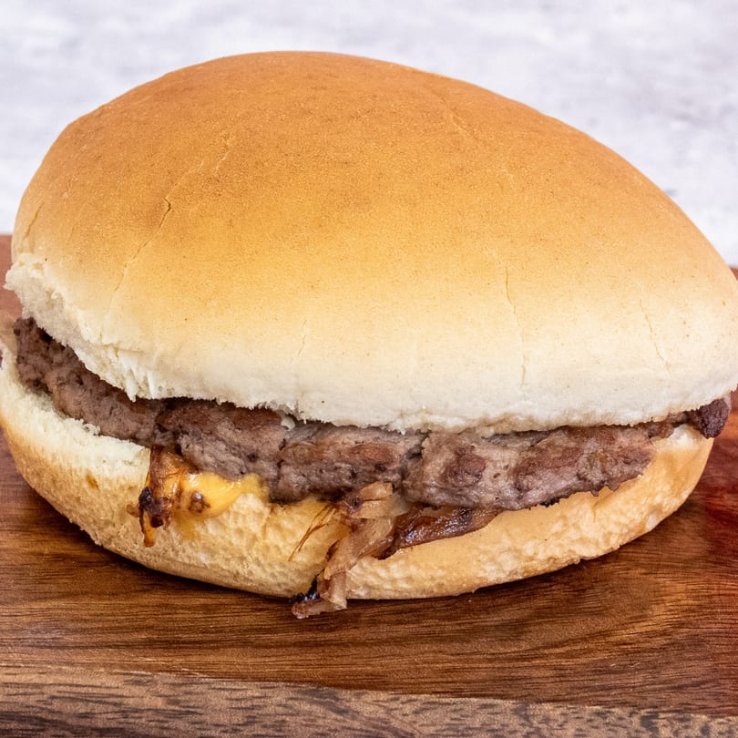 Campus Burgers' classic burger with a beef patty, melted cheese, and caramelized onions on a bun.
