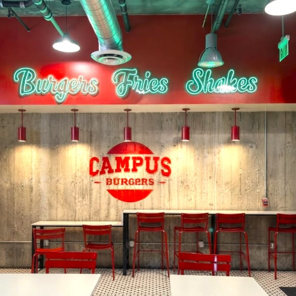 Campus Burgers restaurant interior with red walls, neon signs, concrete wall, and red bar stools.