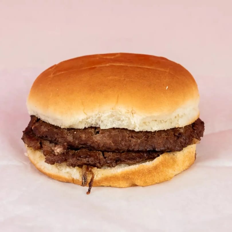 A double cheeseburger with two patties and caramelized onions on a plain bun.